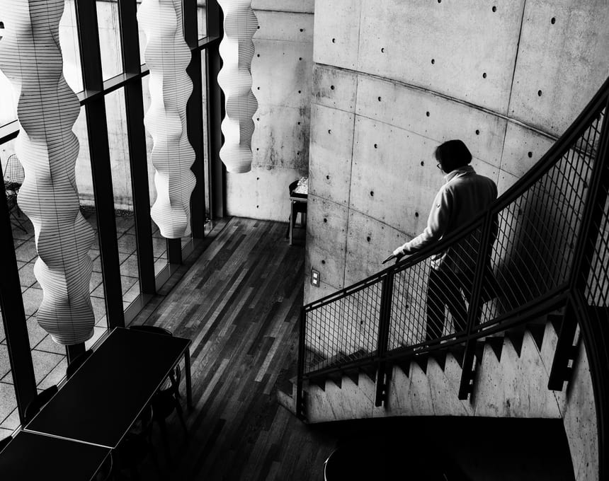 Person descending a concrete staircase inside a modern building.
