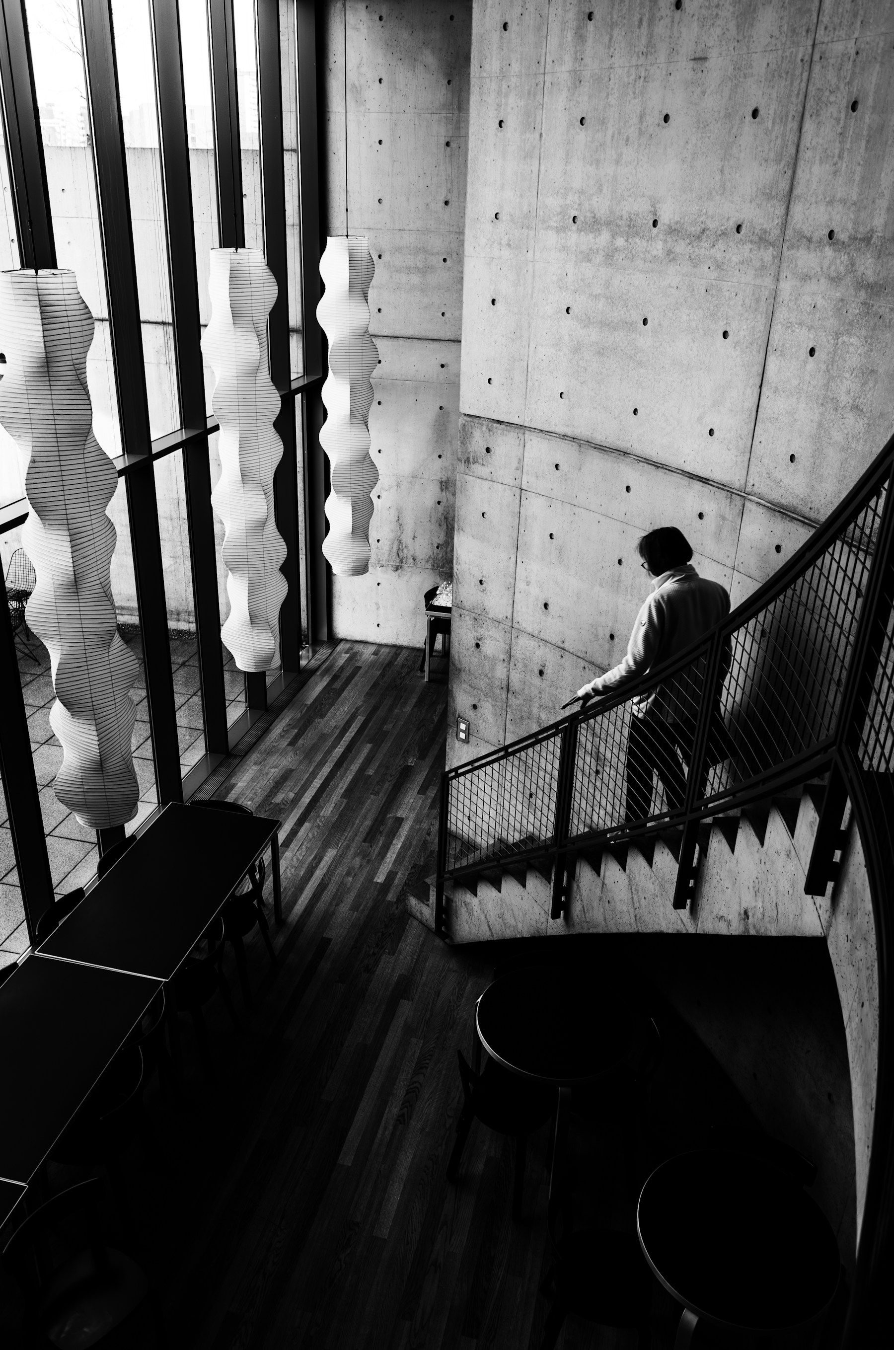 Person descending a modern concrete staircase in strong architectural light.